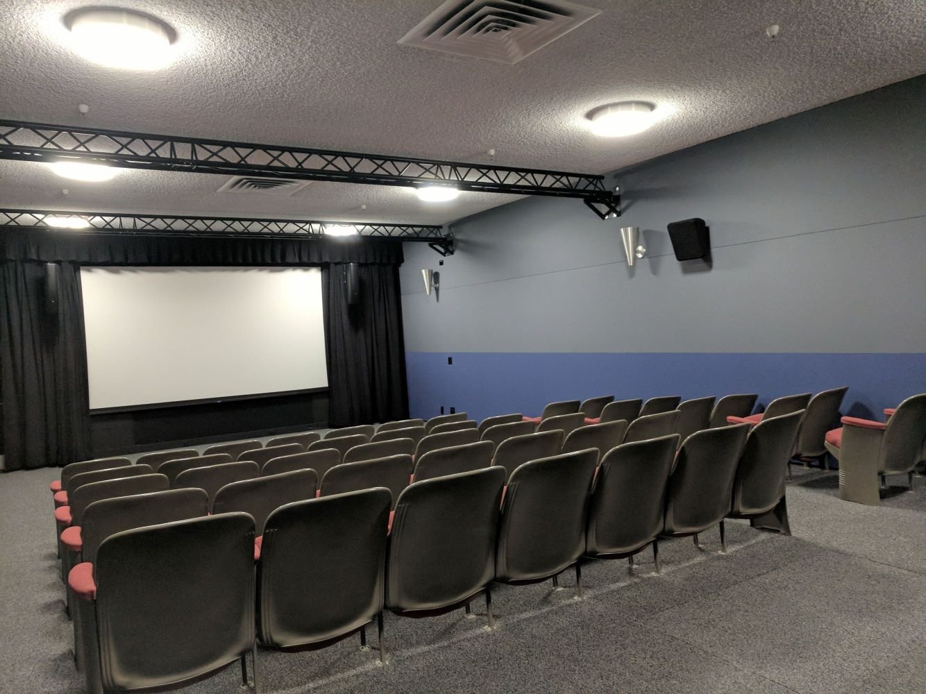 a theater room with a large screen and multiple rows of seats