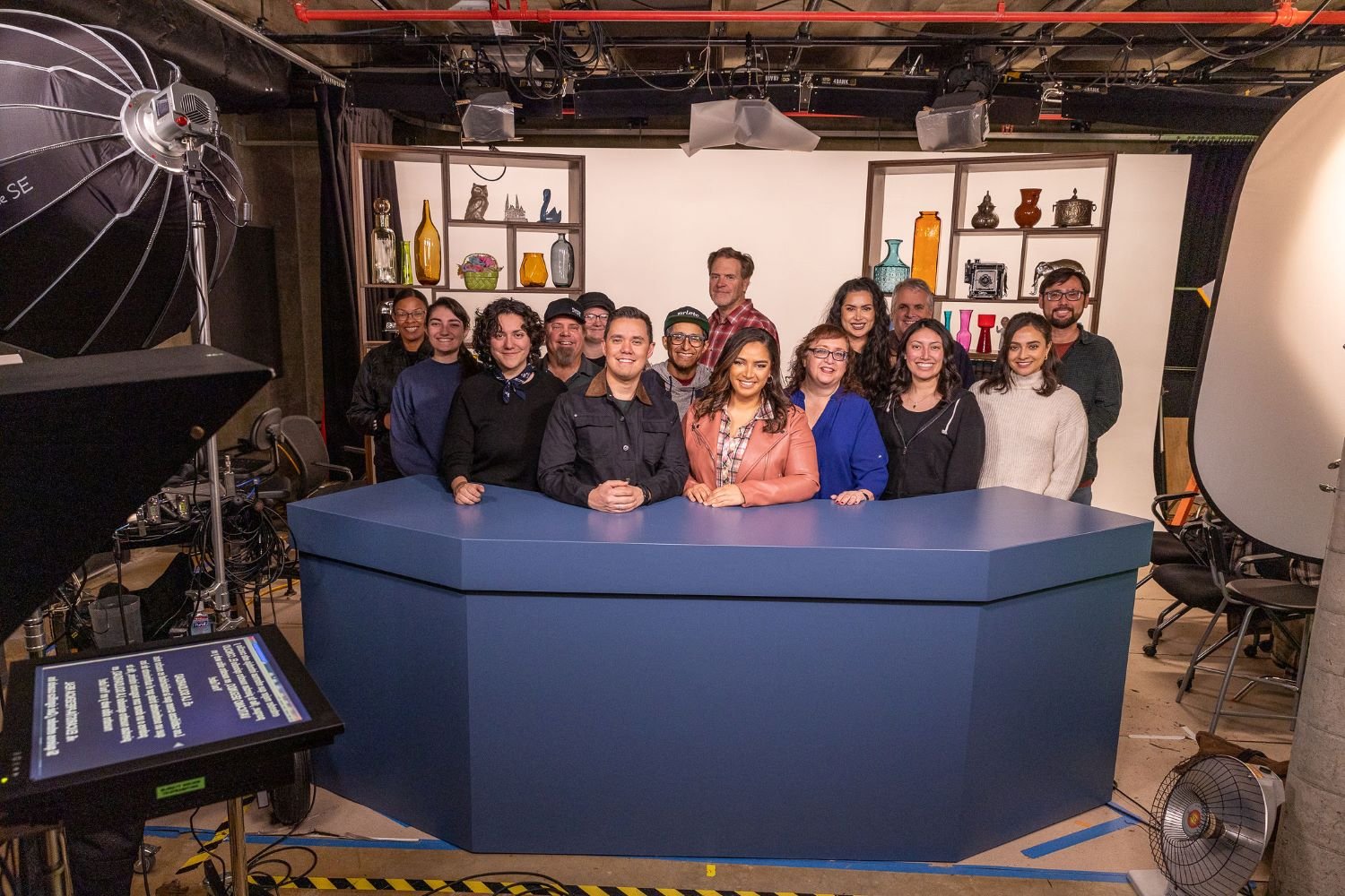 a group of family theater productions staff posing behind a studio desk